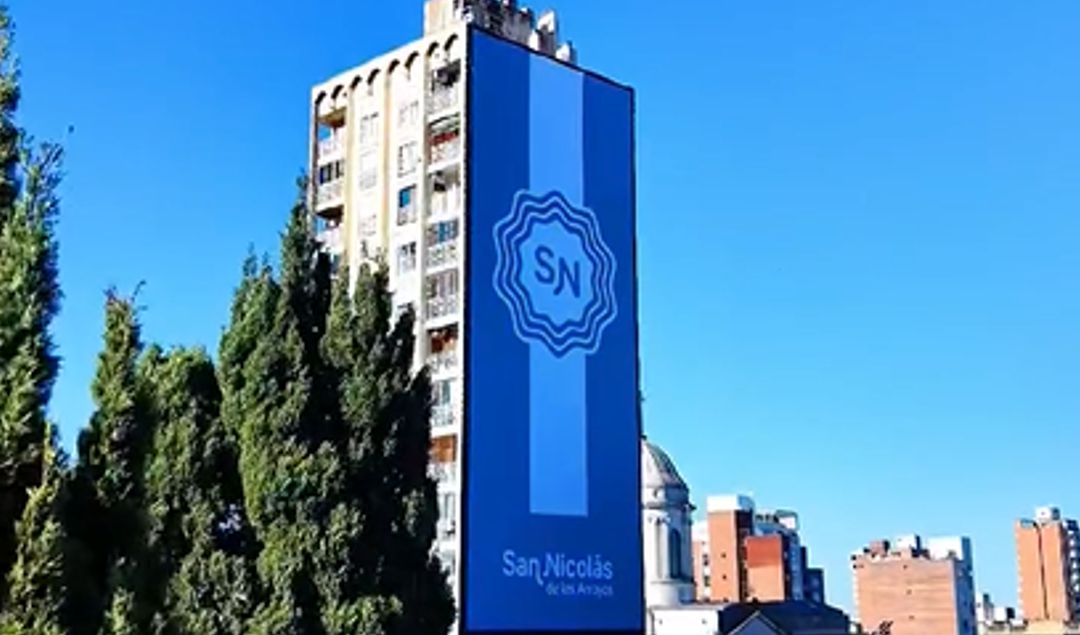 La ciudad de San Nicolás de los Arroyos comenzó a vivir las festividades patrias de mayo con una impactante intervención urbana que rápidamente se volvió furor entre los vecinos. El icónico mural ubicado sobre calle Mitre fue cubierto por una gigantesca escarapela argentina que sorprendió por sus dimensiones y su imponente presencia.
